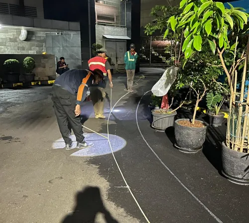 Tim jasa aspal Bogor melakukan pengecekan elevasi dan kemiringan jalan sebelum pengaspalan