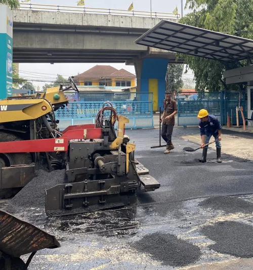 truk tangki aspal curah menyuplai material untuk pengaspalan jalan dengan alat berat