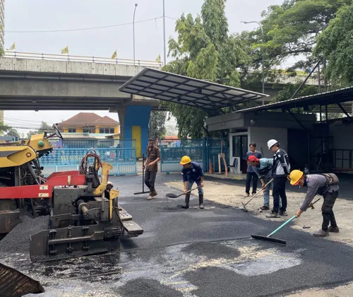 Kegiatan pengaspalan menggunakan aspal Shell di lokasi proyek jalan dengan suasana siang hari dan peralatan konstruksi aktif.