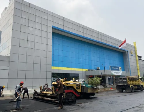 Proses pengerjaan jalan dengan aspal Shell, material hitam panas diratakan di permukaan dengan mesin konstruksi